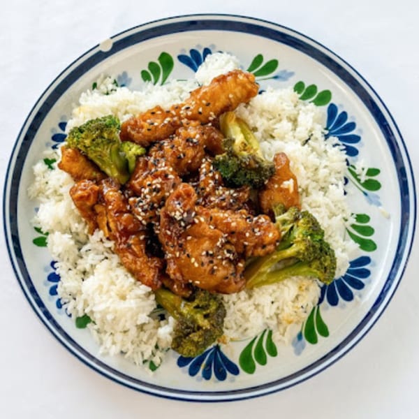 Howard Wang's Preston Hollow's sesame chicken with broccoli and white rice on a decorative plate.