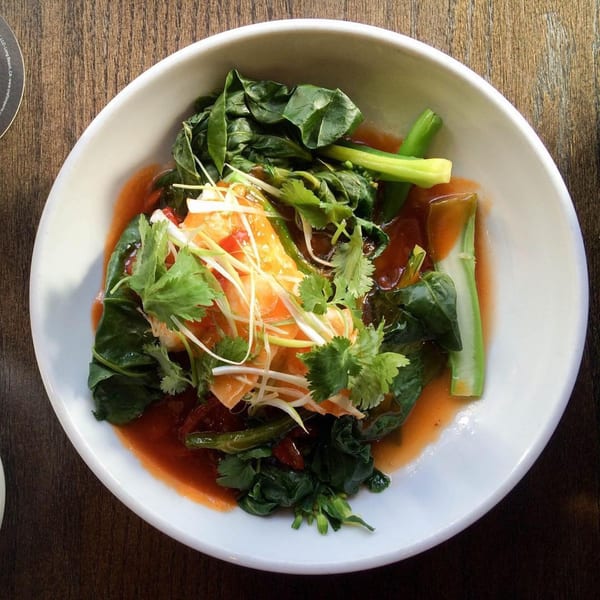 Asian dish with green vegetables, orange sauce, and garnished with cilantro and sliced scallions.